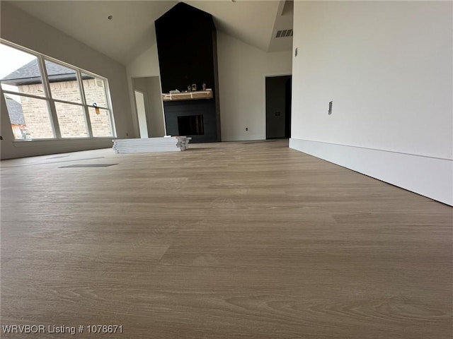 unfurnished living room featuring lofted ceiling and a large fireplace