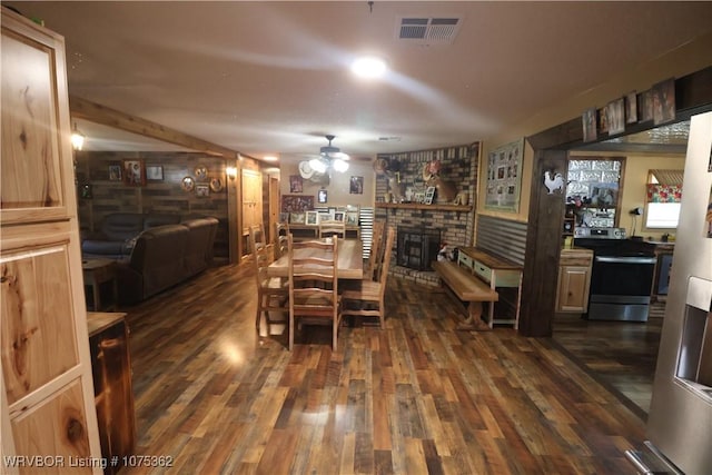 dining room featuring a fireplace, ceiling fan, dark hardwood / wood-style flooring, and brick wall