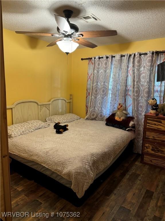 bedroom featuring a textured ceiling, ceiling fan, and dark wood-type flooring