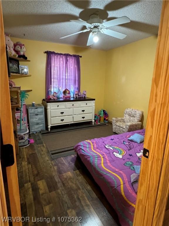 bedroom with hardwood / wood-style floors, ceiling fan, and a textured ceiling