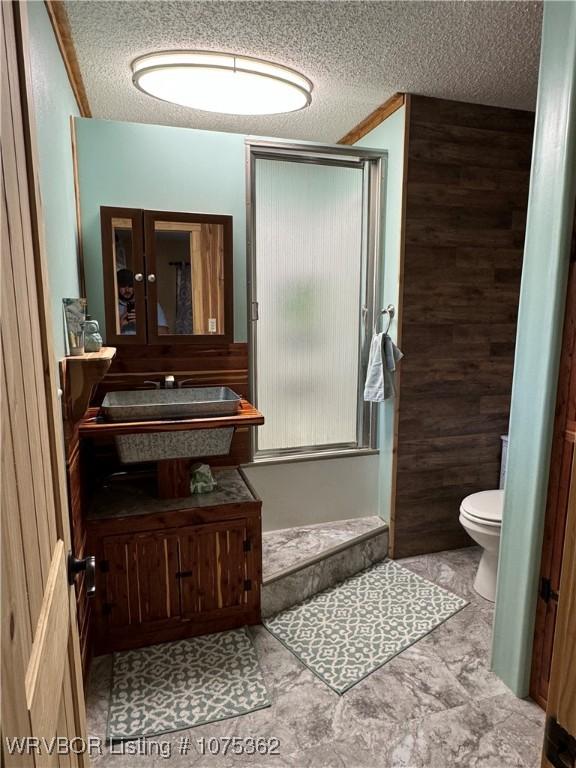 bathroom featuring wood walls, a textured ceiling, and toilet