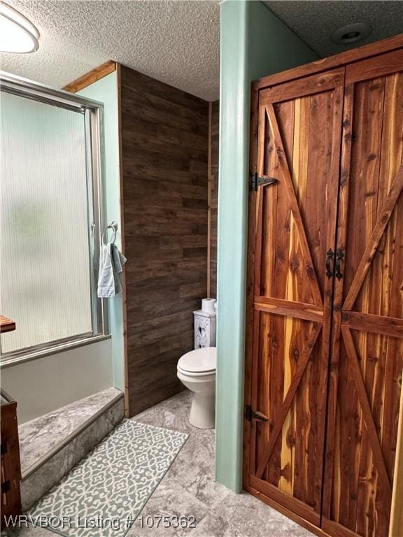 bathroom featuring wood walls, toilet, a textured ceiling, and walk in shower