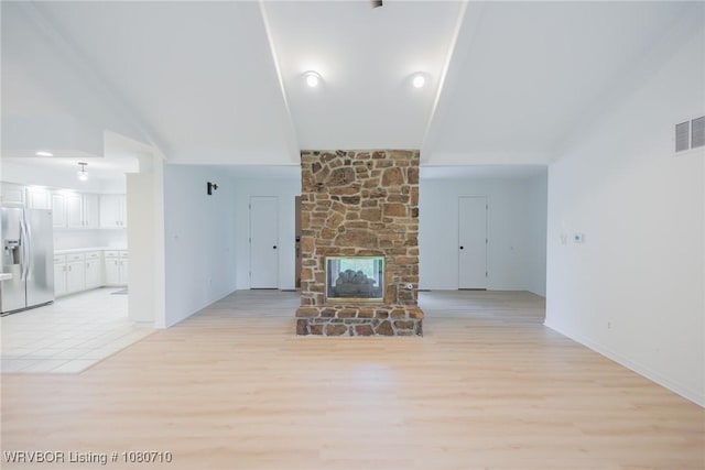 unfurnished living room with baseboards, a fireplace, light wood finished floors, and visible vents