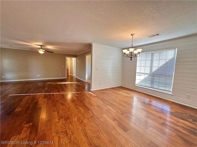 empty room with wooden walls, ceiling fan with notable chandelier, a textured ceiling, and hardwood / wood-style flooring