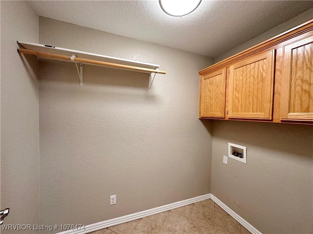 laundry area with washer hookup, cabinets, and a textured ceiling