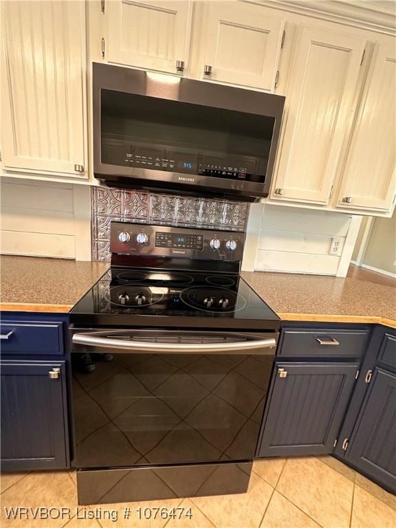 kitchen featuring tasteful backsplash, stainless steel appliances, blue cabinets, light tile patterned floors, and white cabinetry