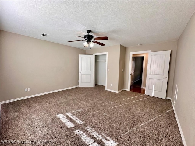 unfurnished bedroom with a textured ceiling, dark carpet, and ceiling fan