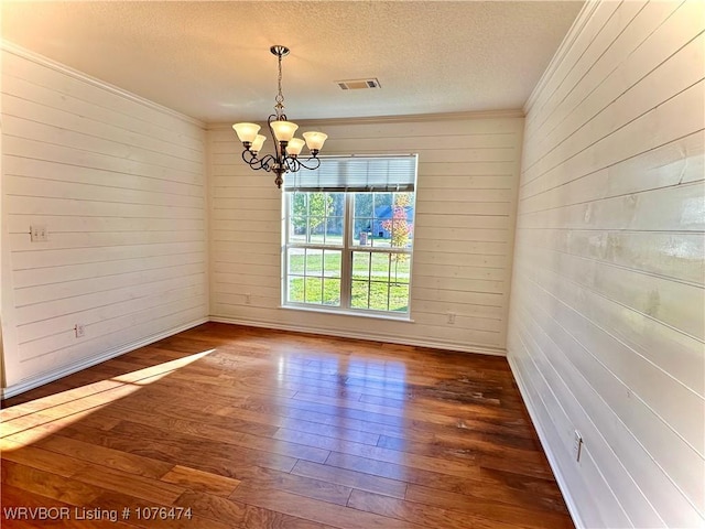 unfurnished room featuring a chandelier, a textured ceiling, dark hardwood / wood-style flooring, and crown molding