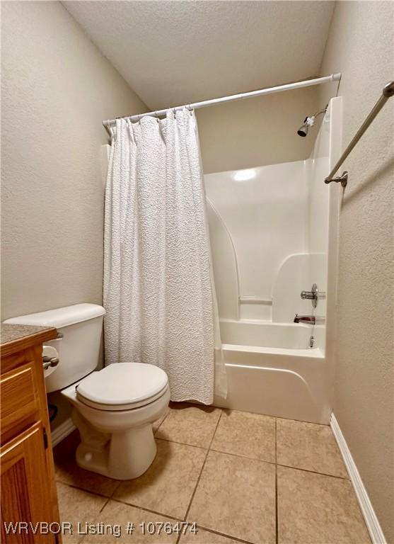 full bathroom featuring vanity, tile patterned floors, toilet, shower / bath combo with shower curtain, and a textured ceiling