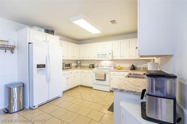 kitchen featuring white appliances, light tile patterned floors, visible vents, a sink, and white cabinetry