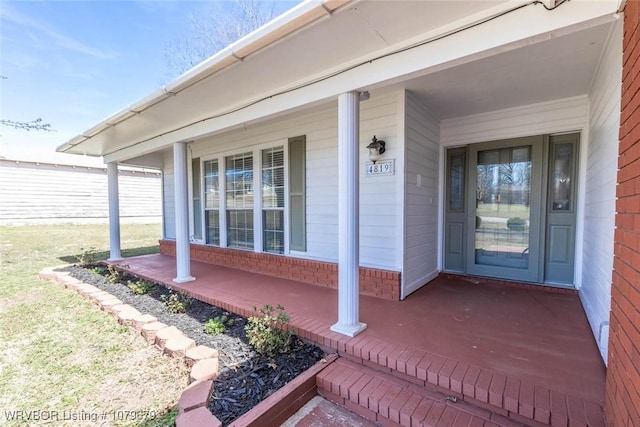 doorway to property featuring brick siding and covered porch