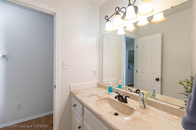 bathroom with vanity, wood finished floors, baseboards, and a chandelier