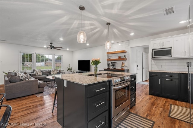 1723 N 52nd St, Fort Smith, AR 72904 - kitchen featuring appliances with stainless steel finishes, white cabinets, tasteful backsplash, a breakfast bar area, and recessed lighting