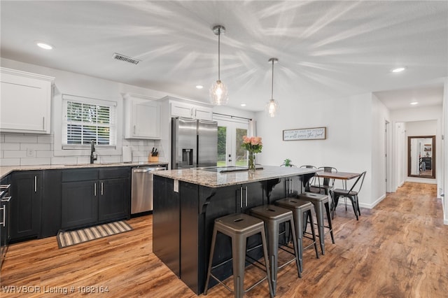 1723 N 52nd St, Fort Smith, AR 72904 - kitchen featuring appliances with stainless steel finishes, light stone counters, a breakfast bar, a kitchen island, and white cabinetry