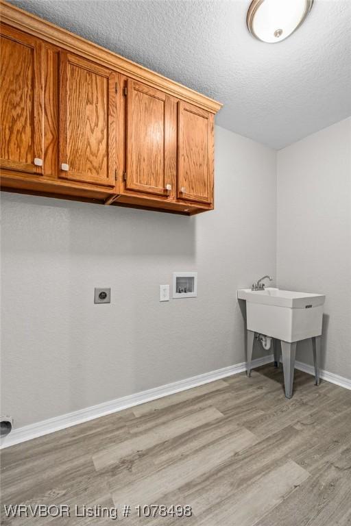 washroom featuring light hardwood / wood-style flooring, washer hookup, a textured ceiling, electric dryer hookup, and cabinets