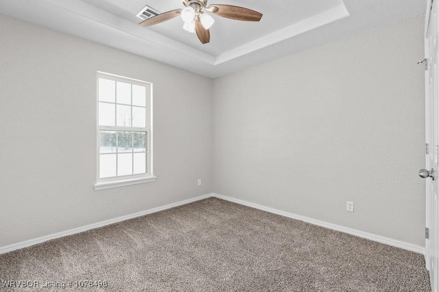 carpeted empty room with ceiling fan and a tray ceiling