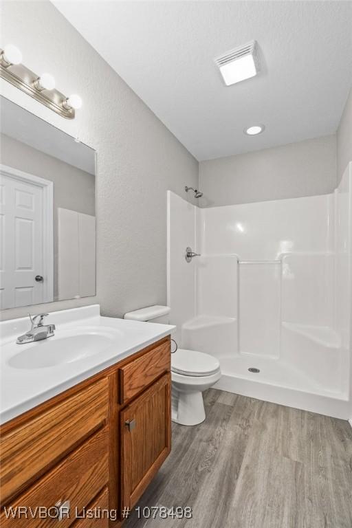 bathroom featuring toilet, a shower, hardwood / wood-style flooring, a textured ceiling, and vanity