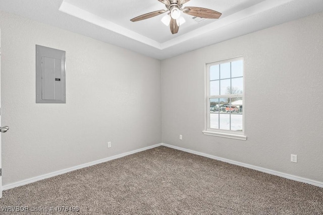 carpeted empty room with a raised ceiling, ceiling fan, and electric panel