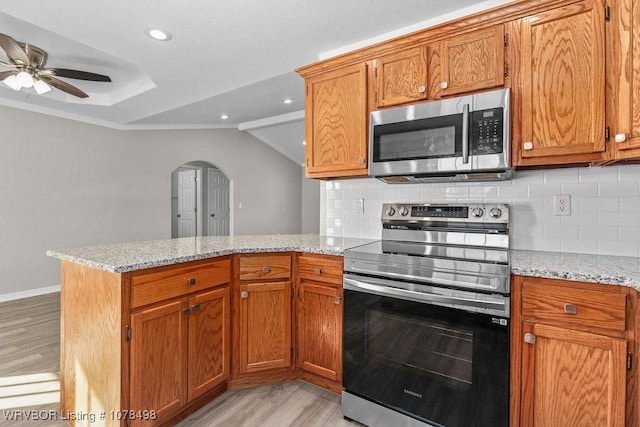 kitchen featuring stainless steel appliances, kitchen peninsula, tasteful backsplash, and light stone countertops