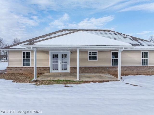 snow covered house featuring french doors and a patio