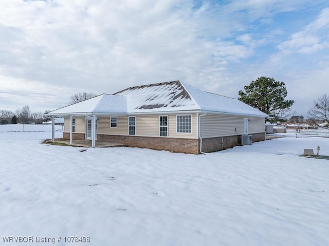 snow covered property with central AC unit