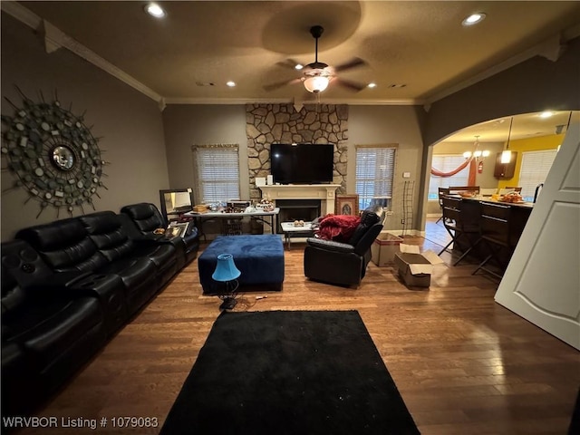 living room with hardwood / wood-style flooring, ornamental molding, a large fireplace, and ceiling fan