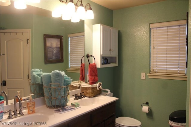 bathroom with toilet, vanity, and a chandelier