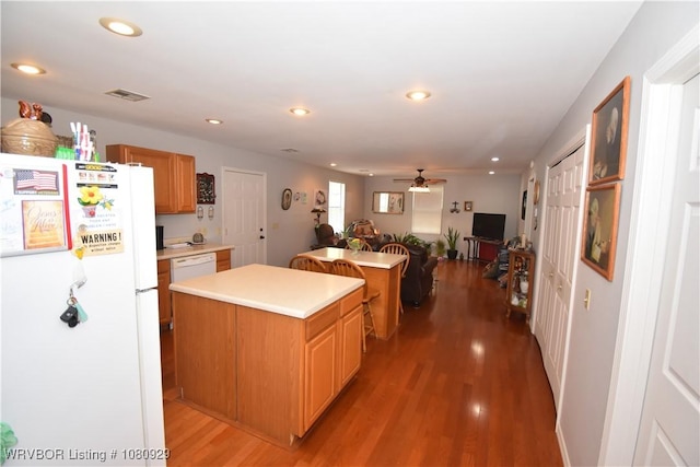 kitchen with white appliances, a center island, light countertops, light wood-style flooring, and ceiling fan