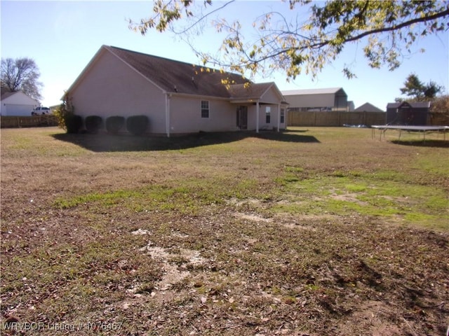 rear view of house featuring a lawn and a trampoline