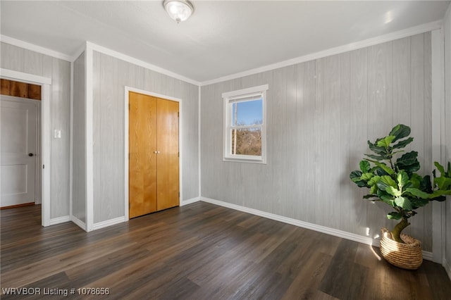 unfurnished bedroom featuring crown molding and dark wood-type flooring