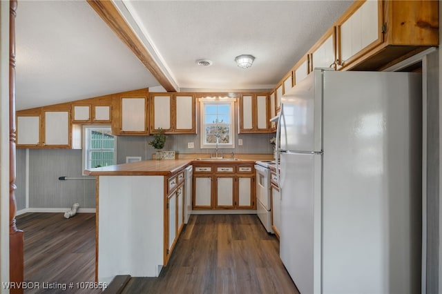 kitchen featuring sink, white appliances, dark wood-type flooring, vaulted ceiling with beams, and kitchen peninsula