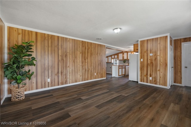 unfurnished living room featuring lofted ceiling, dark wood-type flooring, wooden walls, and ornamental molding