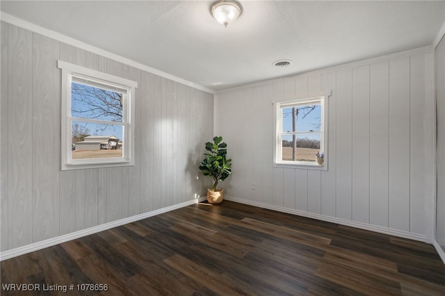 spare room with ornamental molding and dark wood-type flooring