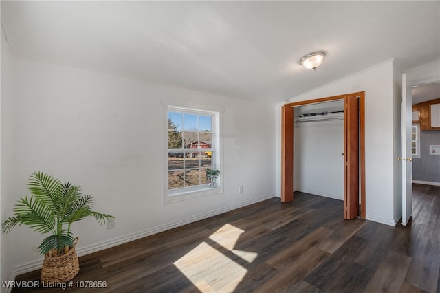 unfurnished bedroom featuring crown molding, dark hardwood / wood-style floors, vaulted ceiling, and a closet