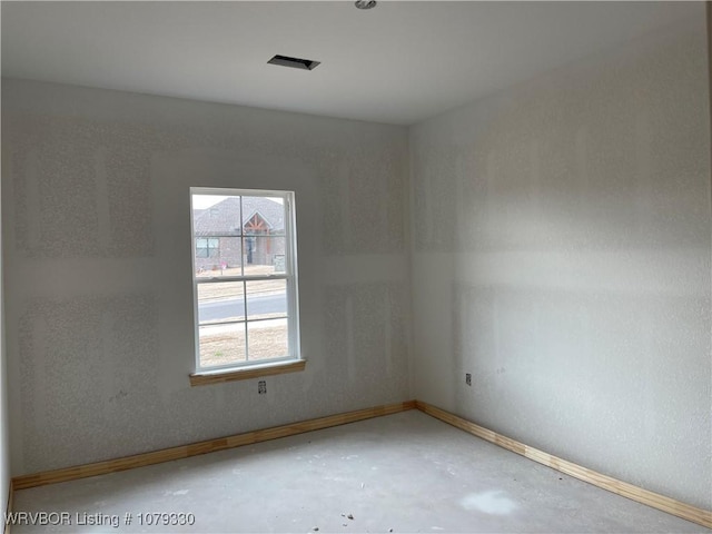 spare room featuring concrete floors, visible vents, and baseboards