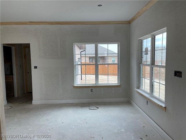 unfurnished room featuring plenty of natural light, baseboards, and crown molding