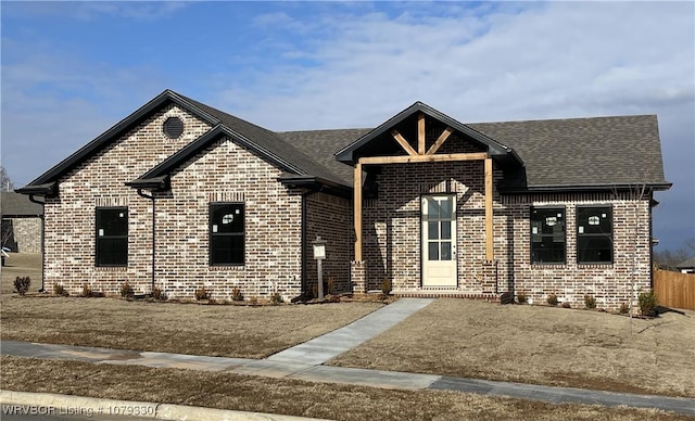 view of front facade with a shingled roof and brick siding