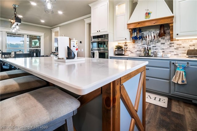 kitchen with white cabinets, premium range hood, double oven, and tasteful backsplash