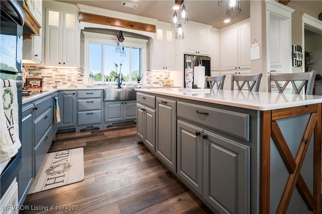 kitchen featuring decorative light fixtures, a kitchen island, white cabinetry, and stainless steel refrigerator