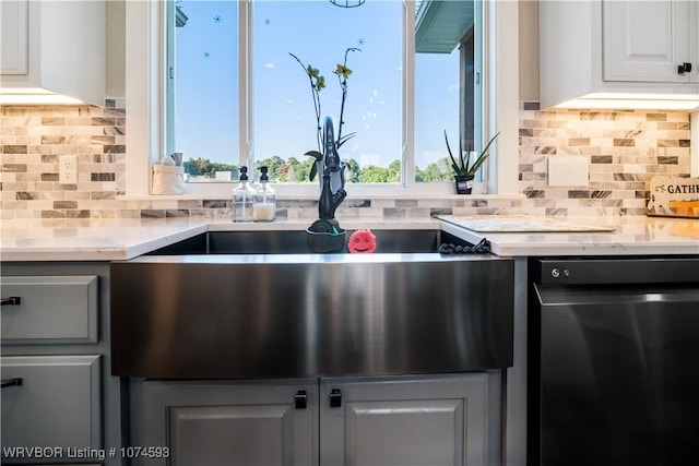 kitchen featuring sink, light stone counters, backsplash, dishwashing machine, and white cabinets