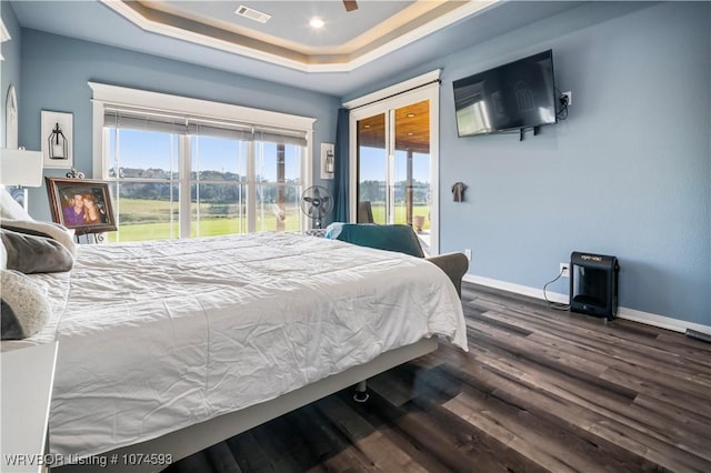 bedroom featuring ceiling fan, dark hardwood / wood-style flooring, and a raised ceiling