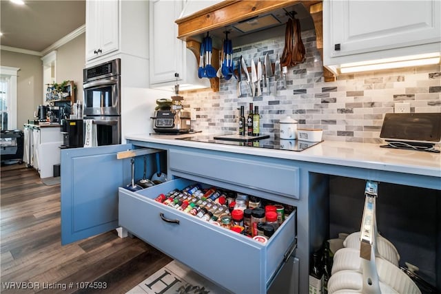 kitchen featuring white cabinets, dark hardwood / wood-style floors, ornamental molding, and double oven