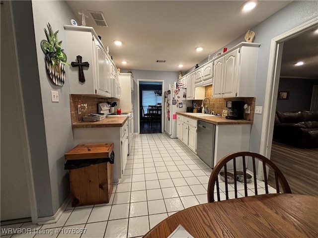 kitchen with backsplash, white appliances, sink, butcher block countertops, and white cabinetry