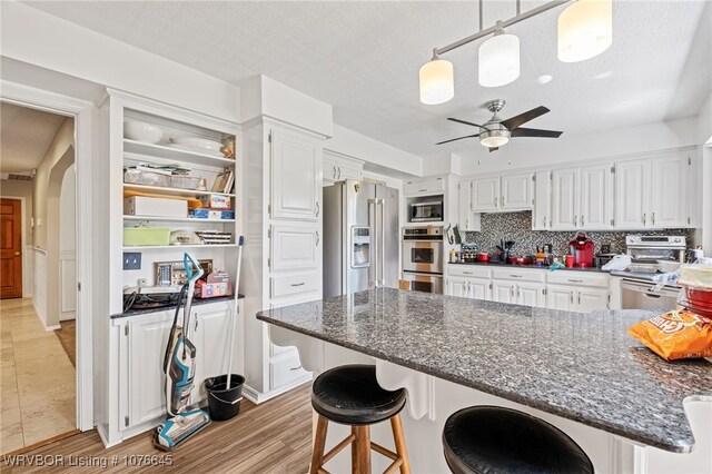 kitchen with appliances with stainless steel finishes, light wood-type flooring, white cabinetry, and ceiling fan