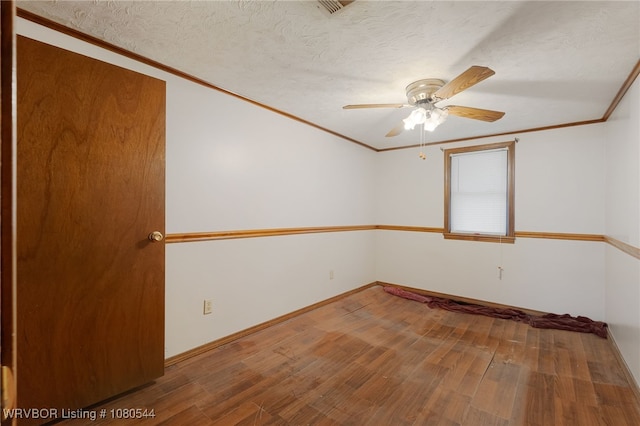 empty room with baseboards, wood finished floors, ceiling fan, and crown molding