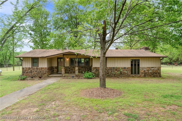 ranch-style home with covered porch, fence, a front lawn, and stone siding