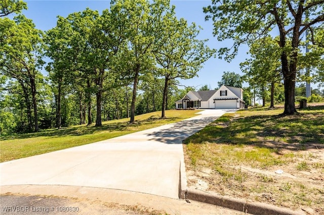 view of front of property featuring concrete driveway, an attached garage, and a front yard