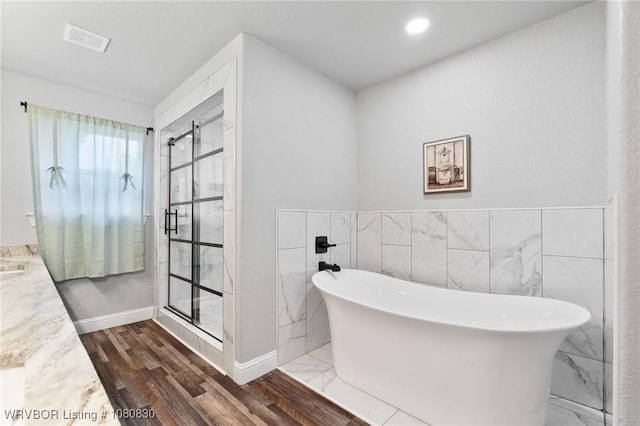 full bathroom featuring a stall shower, vanity, tile walls, and visible vents