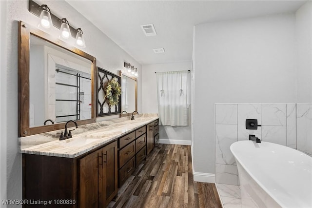 bathroom with a sink, baseboards, visible vents, a freestanding bath, and double vanity