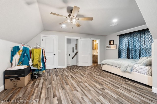 bedroom featuring lofted ceiling, ensuite bathroom, wood finished floors, ceiling fan, and baseboards